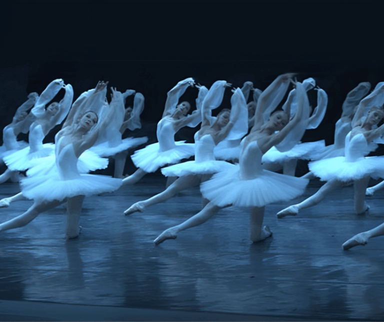 Dancers in white tutus perform a graceful synchronized movement on stage during La Bayadère, capturing the elegance and intensity of the most emotional classical ballet.