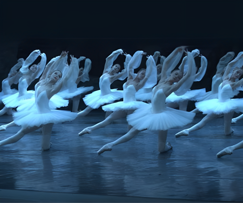 Dancers in white tutus perform a graceful synchronized movement on stage during La Bayadère, capturing the elegance and intensity of the most emotional classical ballet.